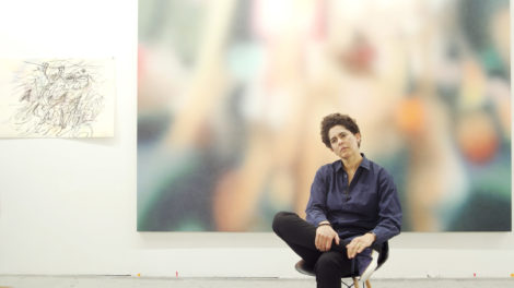 Artist Julie Mehretu sits on a chair in a studio