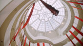 Various large wool strands in different shades of red hanging from the spiral ramps in the Guggenheim Museum.