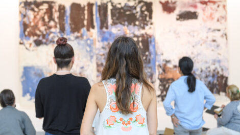 A group of teachers stands with their backs to the camera while observing a large abstract painting.