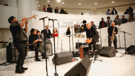 A multi-instrumentalist band performs music on a white stage during the opening reception for Rashid Johnson: A Poem for Deep Thinkers.